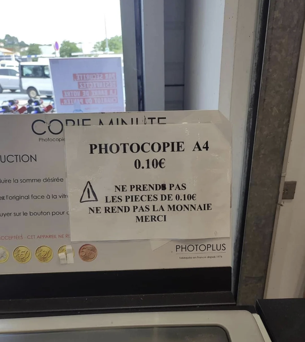 Panneau sur une photocopieuse indiquant PHOTOCOPIE A4 0.10€ et NE PRENDS PAS LES PIECES DE 0.10€ NE REND PAS LA MONNAIE MERCI. Pièces de monnaie visibles.