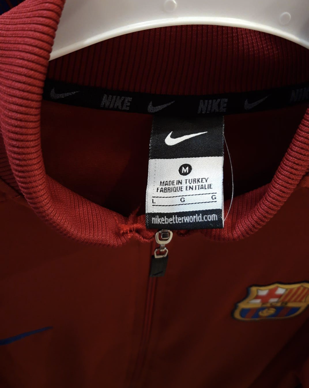 Gros plan de l'étiquette intérieure d'une veste rouge Nike avec logo FC Barcelone, mention 'Made in Turkey' et 'Fabriqué en Italie'.